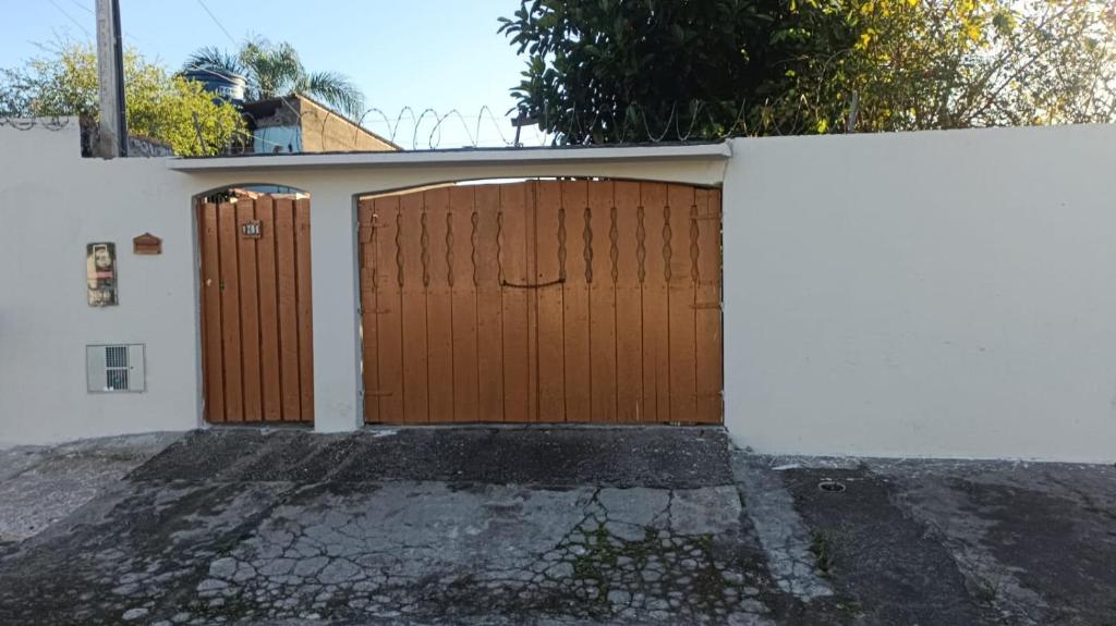 a garage with two brown doors on a white wall at Casa top com piscina em Mongaguá in Mongaguá
