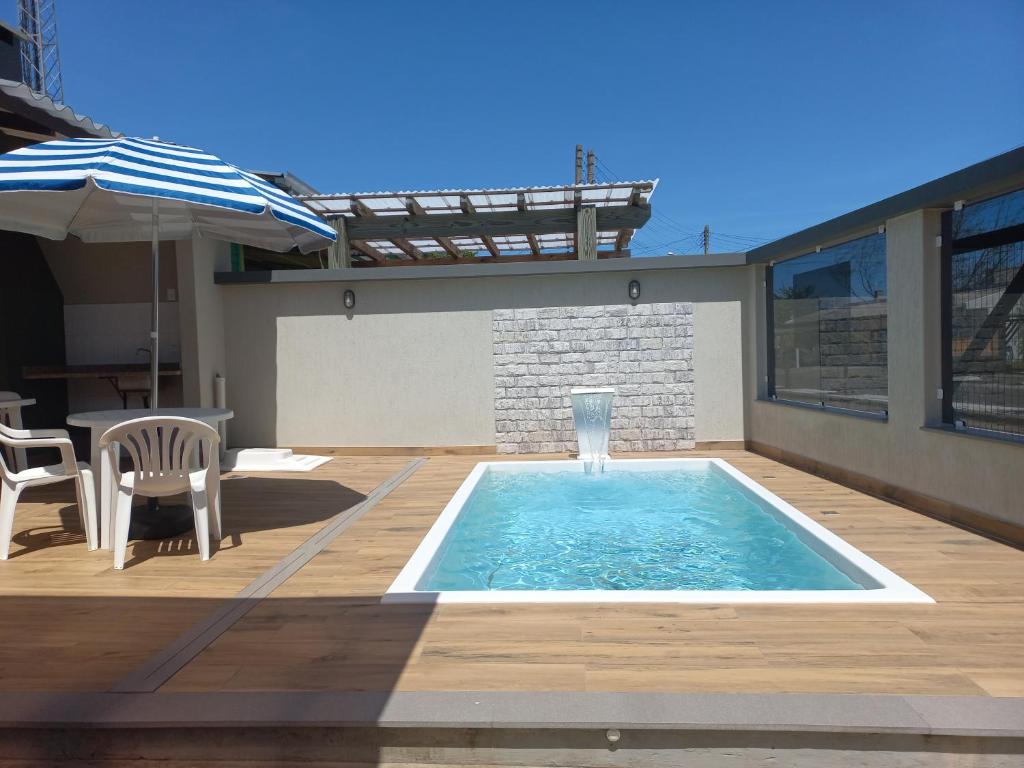 ein Swimmingpool auf einer Terrasse mit einem Tisch und einem Sonnenschirm in der Unterkunft Casa Com Piscina Pertinho Do Mar Em Capão Da Canoa in Capão da Canoa
