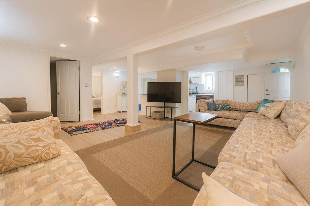un salon avec un canapé et une télévision dans l'établissement Melrose Place Poolside Hideaway Basement Suite Sleeps 6 plus, à Victoria