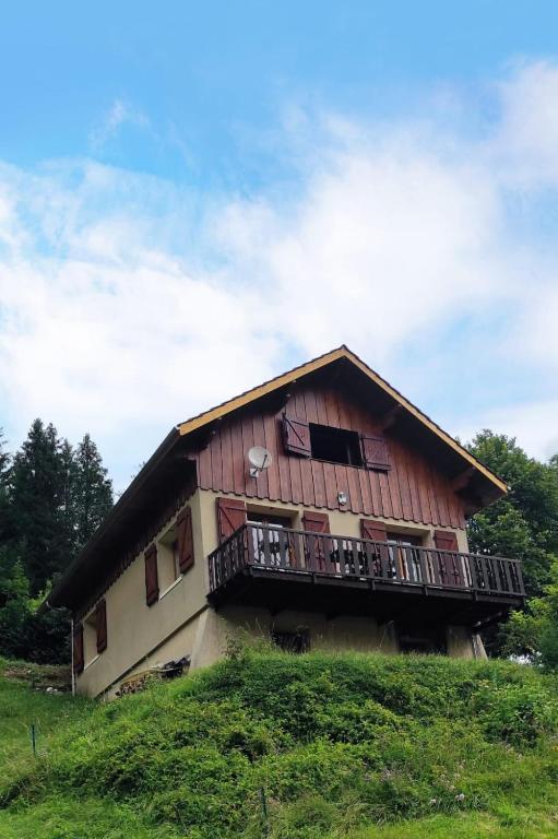 a wooden house with a balcony on a hill at Chalet des ORCHIDÉES en Chartreuse in Saint-Pierre-dʼEntremont