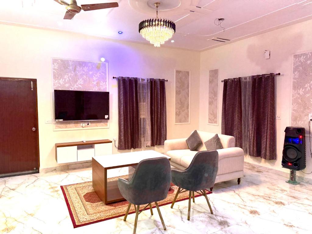 诺伊达ParkHaven Luxury Villa with Garden View的客厅配有沙发、电视和椅子