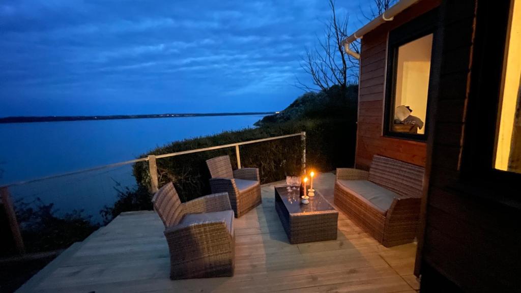 een terras met stoelen en een tafel met een kaars bij Cabane front de mer in Saint-Brieuc