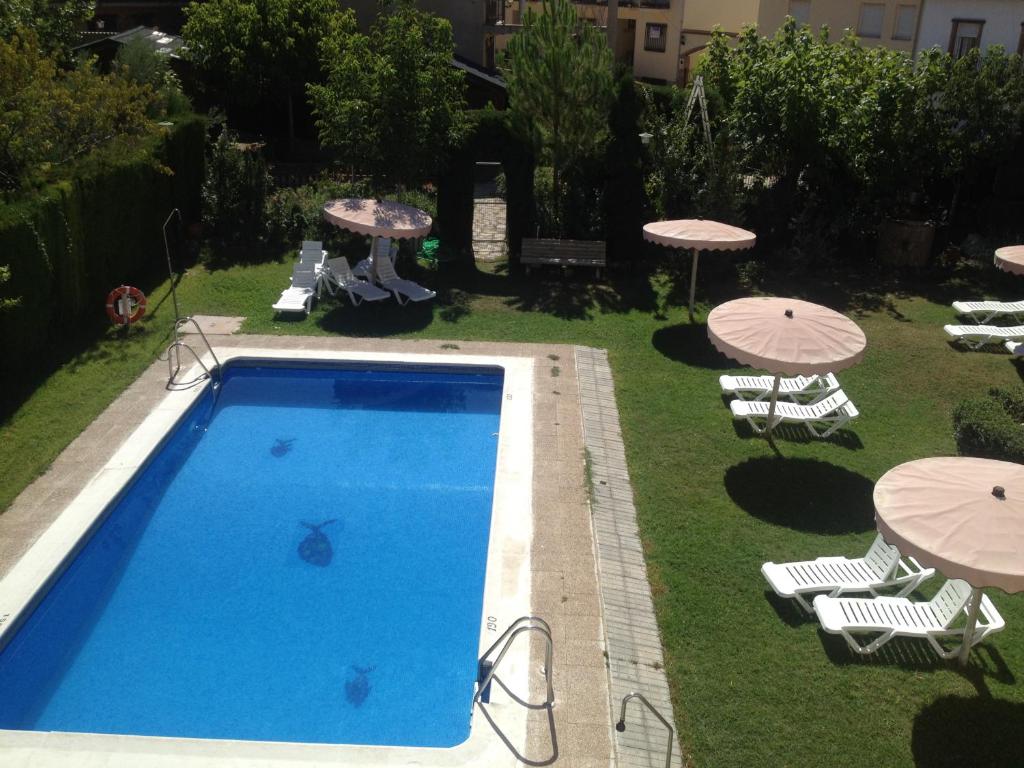 una piscina con sombrillas, sillas y una mesa en Apartamentos Arroyo Frío, en Arroyo Frío