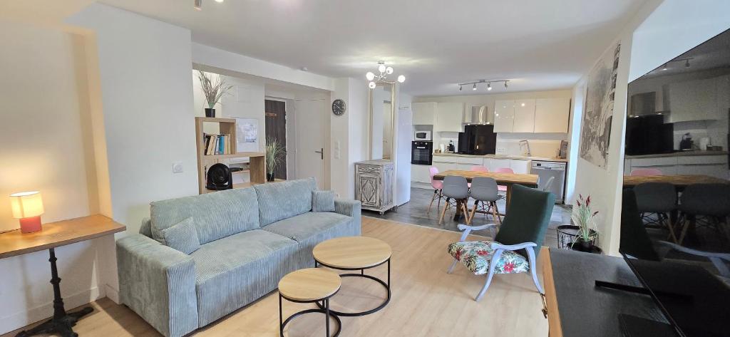 a living room with a blue couch and a kitchen at Le Charme du Sanctuaire 8 couchages 400m de la Grotte in Lourdes