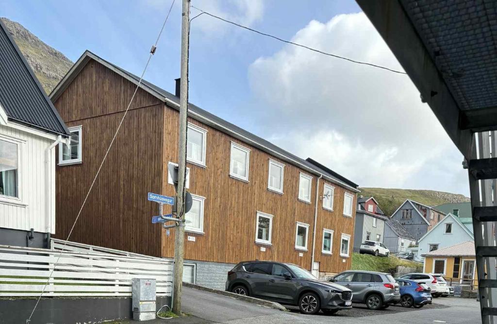 un groupe de voitures garées devant un bâtiment dans l'établissement Midbrekkan Guesthouse, à Tvøroyri