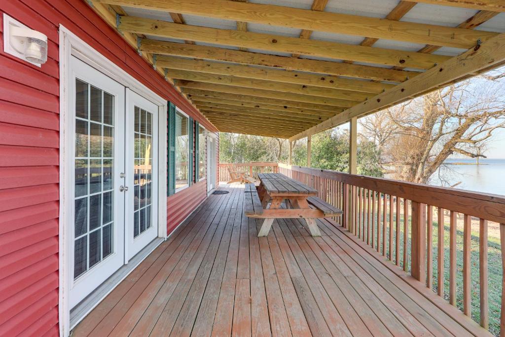 a wooden deck with a picnic bench on a red house at Spacious Family Winter Retreat on Oneida Lake! in Canastota