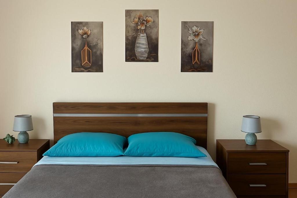 a bedroom with a bed with three paintings on the wall at Tiny apartment near the airport in Ponta Delgada