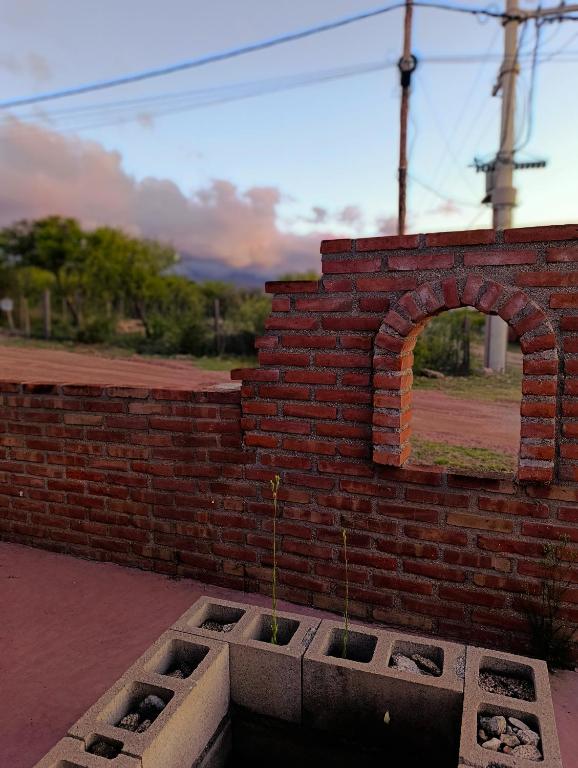 Arroyo de Los PatosCabañita hacia las cumbres的一面砖墙，墙上有一扇窗户，旁边有一些植物。