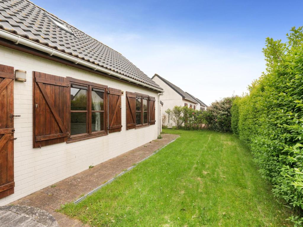 a house with wooden windows and a green yard at Zeepark Haerendycke - Vakantiewoning 40 in De Haan