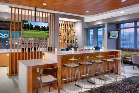 Una habitación con una barra con taburetes y un campo de golf. en SpringHill Suites North Airforce Academy, en Colorado Springs
