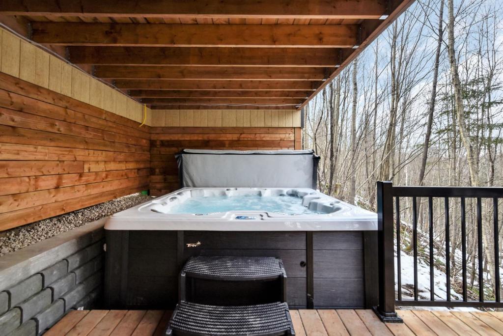 ein Whirlpool auf einer Terrasse mit einem Stuhl in der Unterkunft Charmant Boisé - Nature spa et sauna in Pont-Rouge