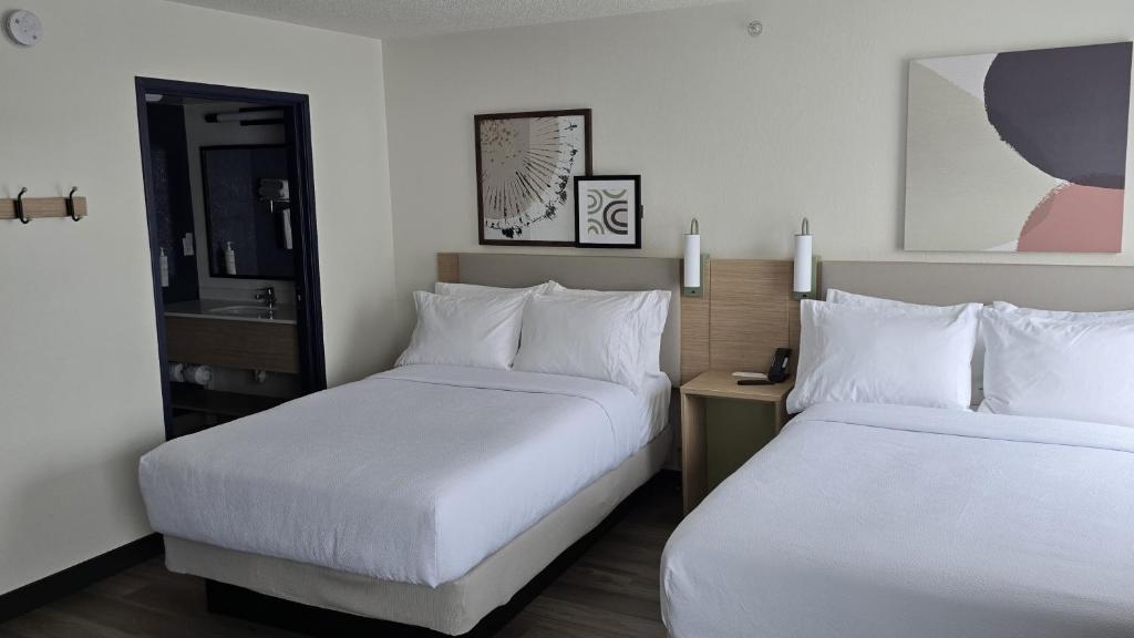 una camera d'albergo con due letti e uno specchio di Spark By Hilton Wilmington a Wilmington