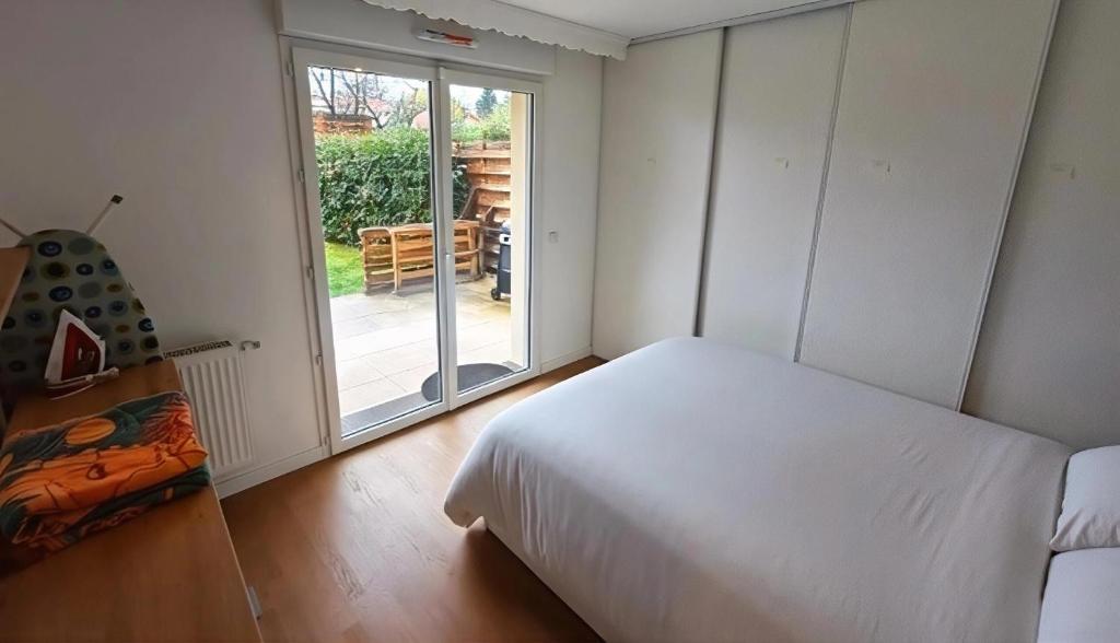 een slaapkamer met een wit bed en een glazen schuifdeur bij Anton's Home in LʼHay-les-Roses