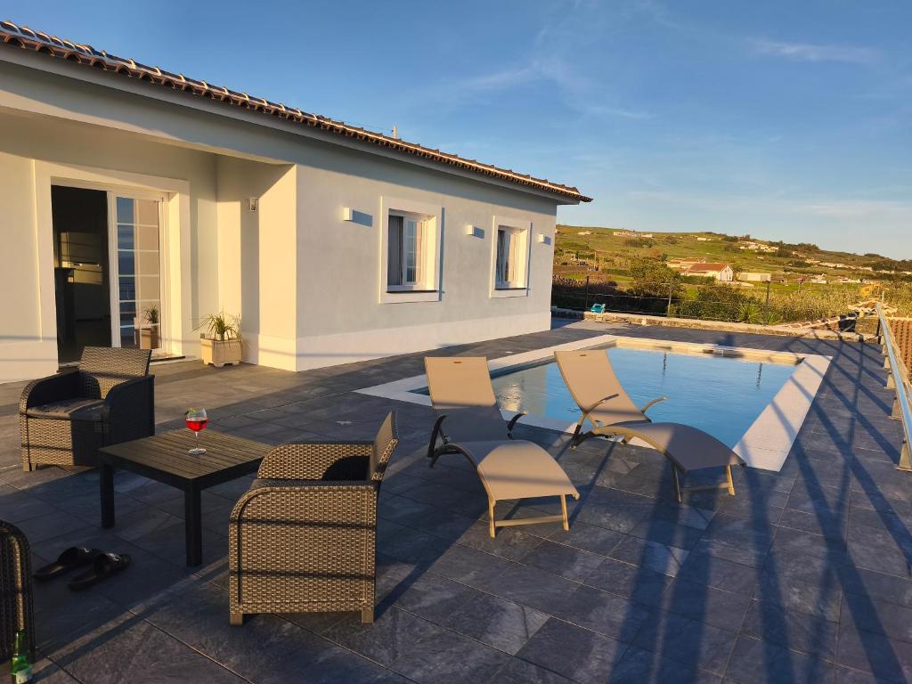 a patio with chairs and a table and a pool at Cantinho do alto in Porto Judeu