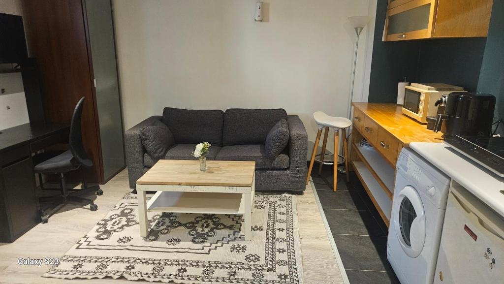 een woonkamer met een bank en een salontafel bij Charmant studio in Élancourt