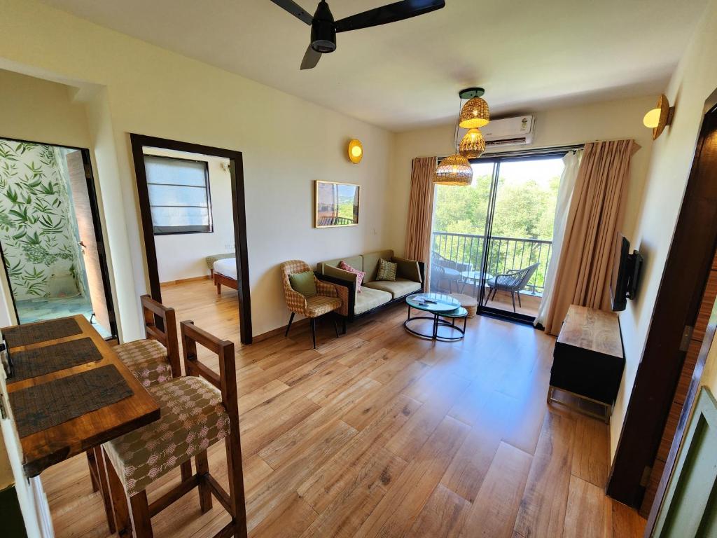 Warm 2BHK with Scenic Mangrove View in Candolim Goa في كاندوليم: غرفة معيشة مع طاولة وكراسي وأريكة
