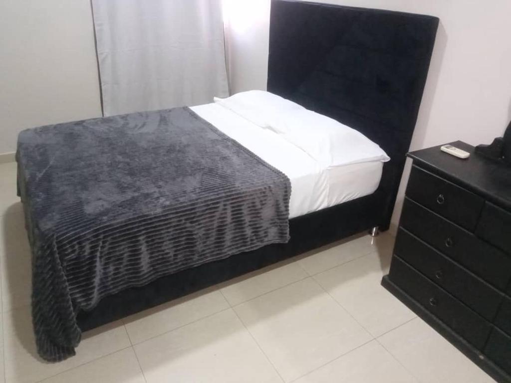 a bedroom with a black bed and a dresser at Torre Imperial Apartamento in Maracay