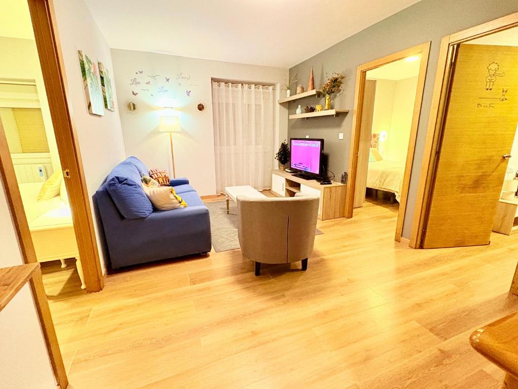 a living room with a blue couch and a television at Casa CAMPELO- Playas de Pinténs - CANGAS-HIO- Ría de Aldán in Cangas de Morrazo