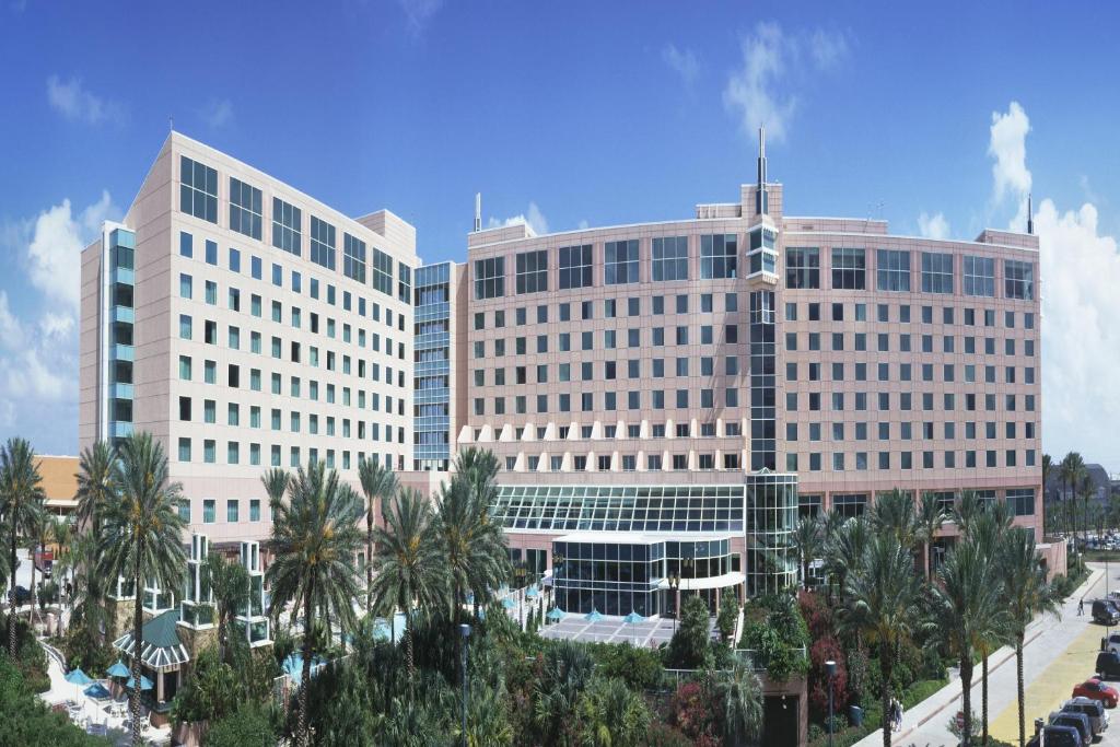 2 grands bâtiments blancs avec des palmiers devant dans l'établissement Moody Gardens Hotel Spa and Convention Center, à Galveston