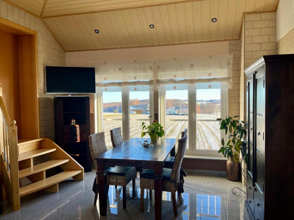 ein Esszimmer mit Tisch und Stühlen und Fenstern in der Unterkunft Fernblick Giershagen in Marsberg