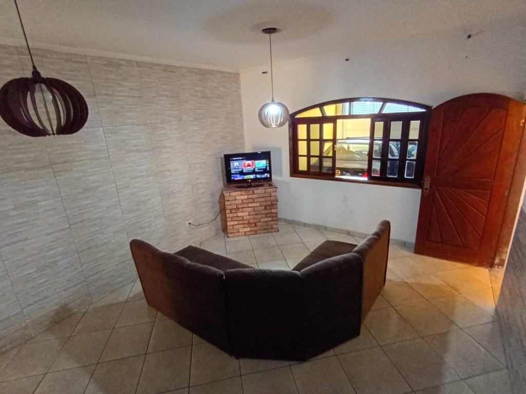a living room with a couch and a television at Haja Luz Casa Pousada 1 em Itaquaquecetuba in Itaquaquecetuba