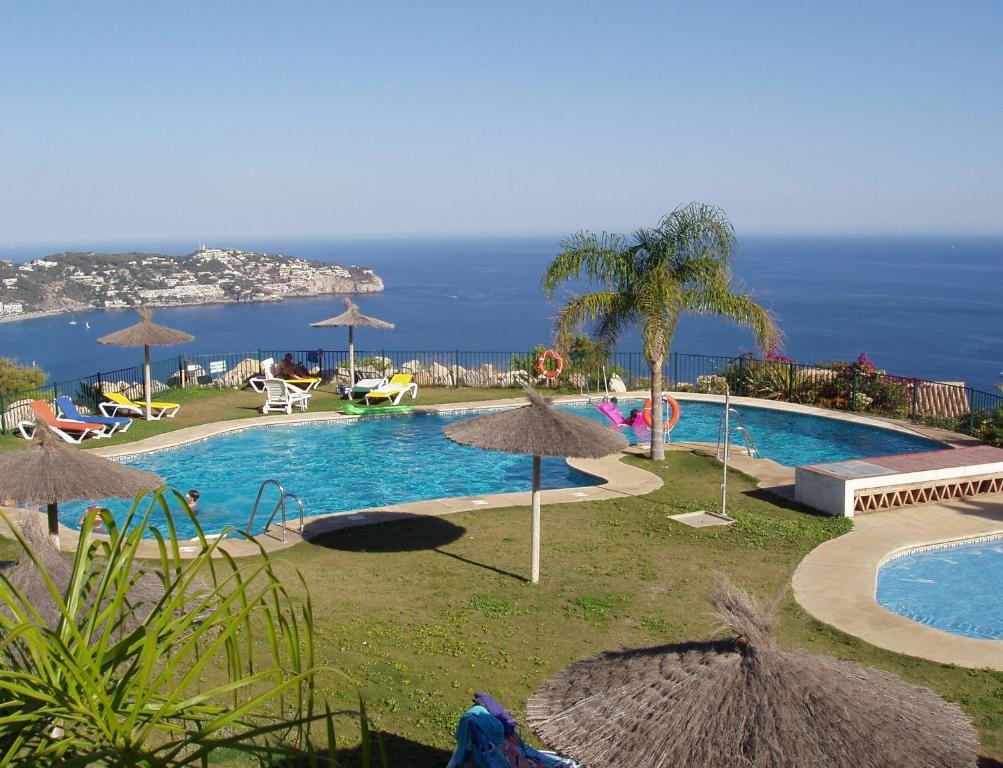 a swimming pool with umbrellas and the ocean in the background at Casa José in La Herradura