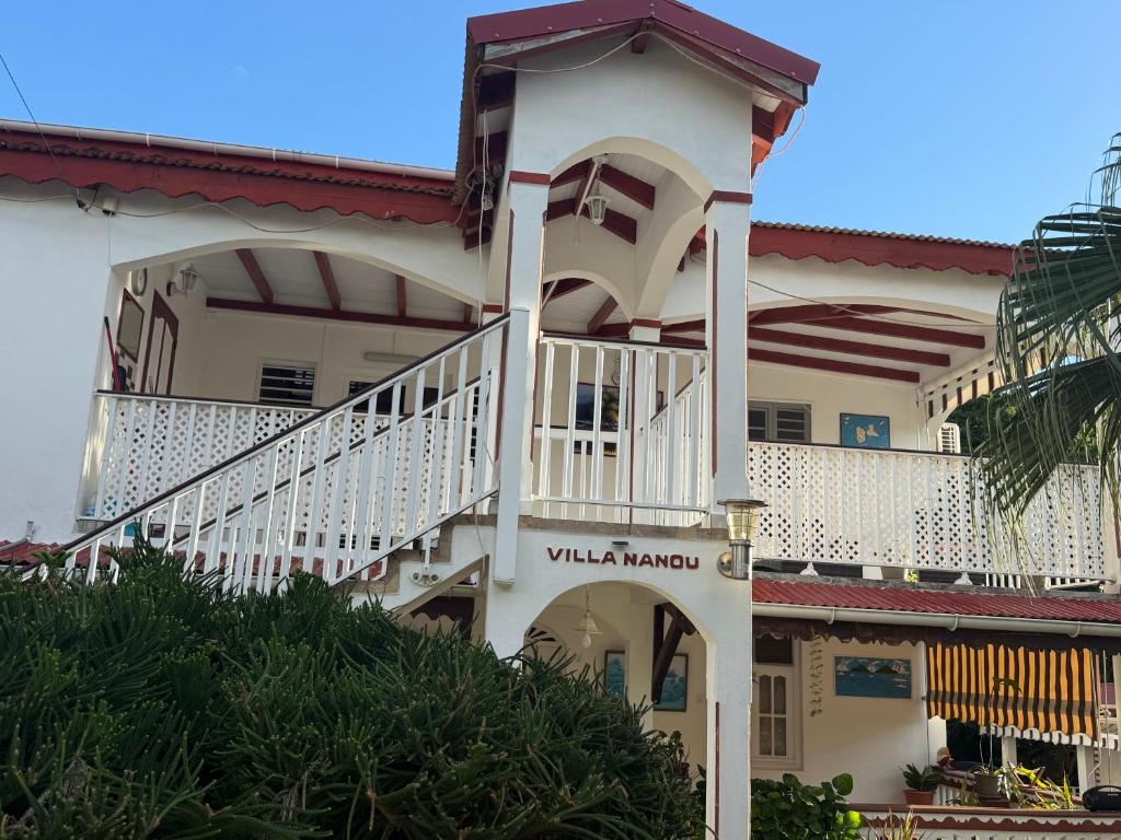 a large white house with a staircase on it at Villa Nanou , Haut de villa calme et petite vue sur Mer in Bouillante