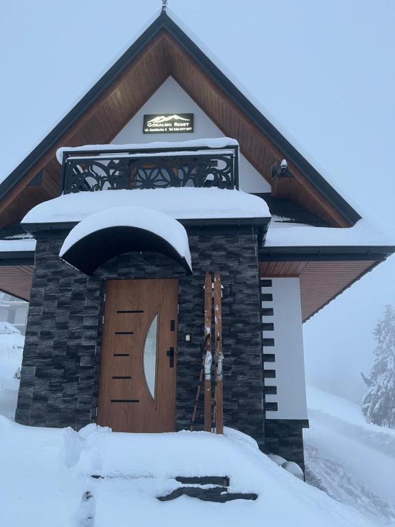 un bâtiment avec une porte recouverte de neige dans l'établissement Domek Góralski Reset, à Gliczarów Górny