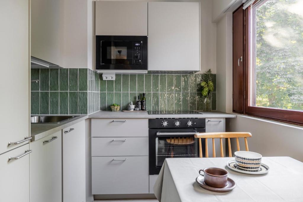 a kitchen with white cabinets and a table and a window at Stylish marine studio, balcony, parking in Lauttasaari in Helsinki