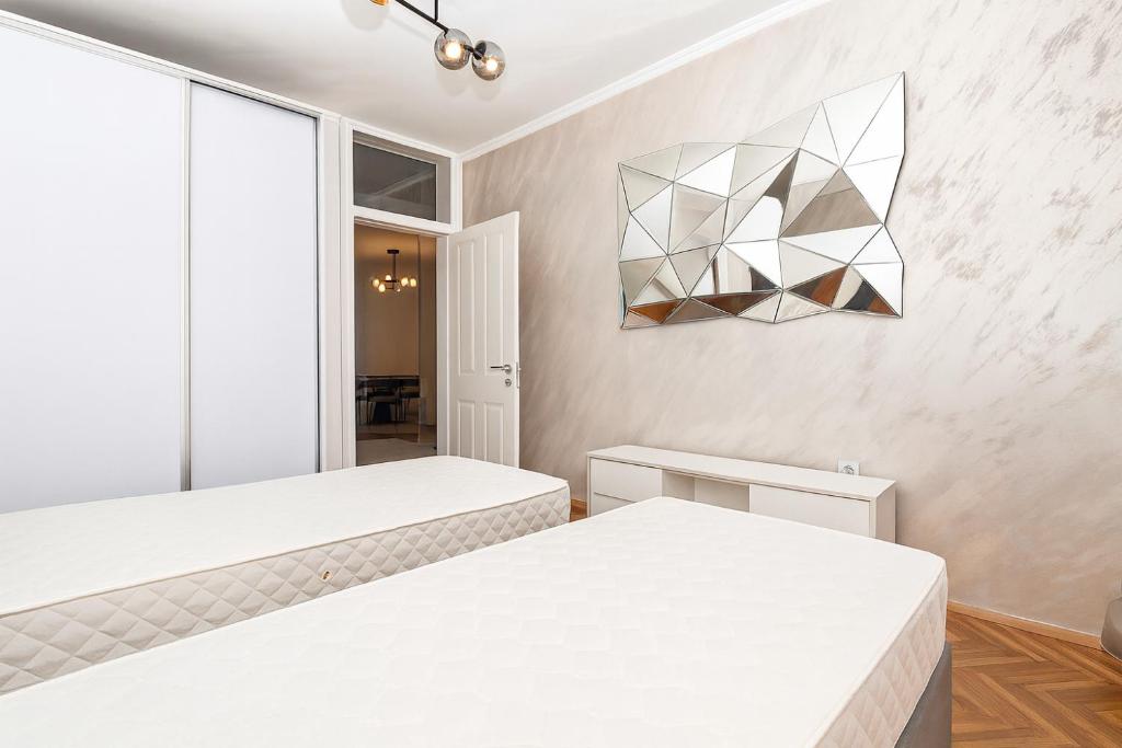 ポドゴリツァにあるWhite Lounge Haustorのベッド2台とシャンデリアのある寝室