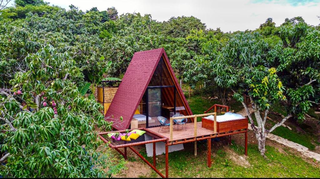 a small house with a red roof in a forest at Glamping Entre Mangos in La Mesa