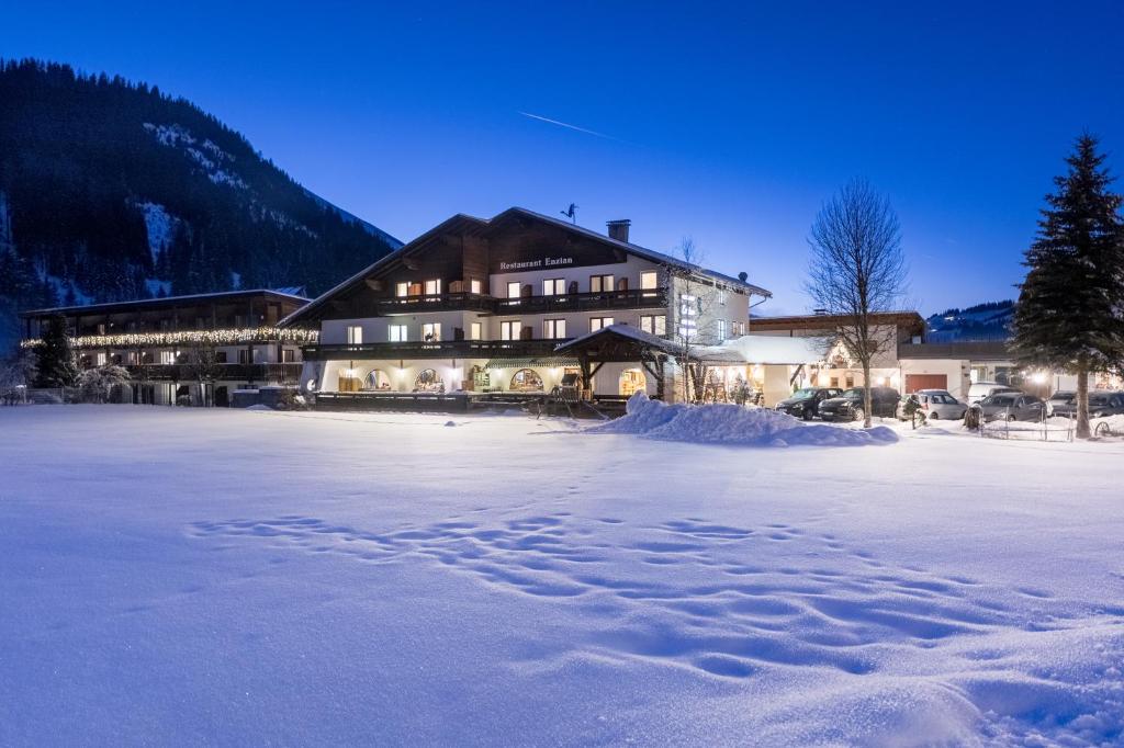 un gran edificio en la nieve con huellas en la nieve en Gasthof Enzian, en Tannheim