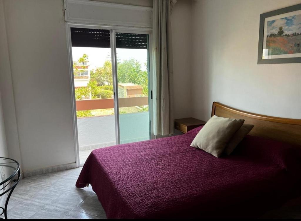 Un dormitorio con una cama con una manta morada. en Resedence lettoral, en Mohammedia