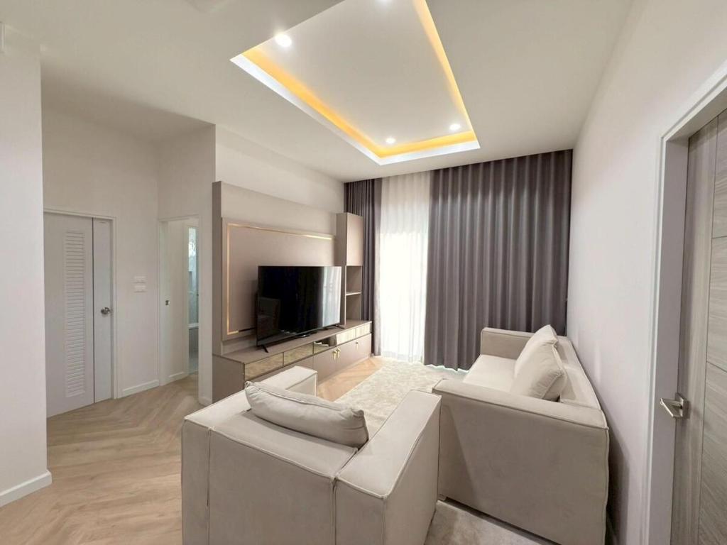 a living room with a couch and a television at Tropical home close to nature and city in Ban Mai I