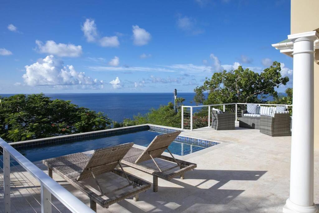 a swimming pool with two chairs and the ocean at Maria Bluff Cottage Villa-Romantic Ocean Views Modern Private Pool in Contant