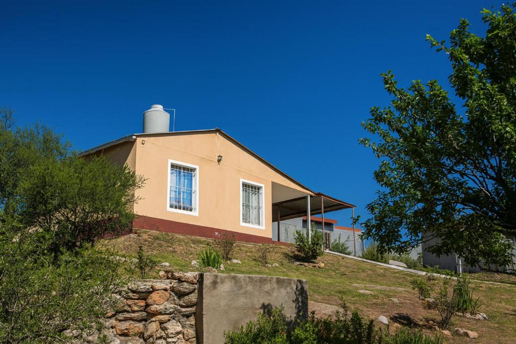 ein Haus auf einem Hügel mit einem Baum in der Unterkunft El Roble, casa de sierra in Estancia Vieja