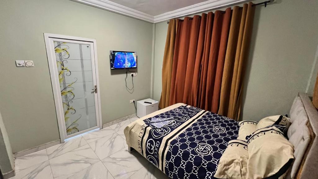 Un dormitorio con una cama y un televisor de pantalla plana. en Prof's Villa, en Kumasi