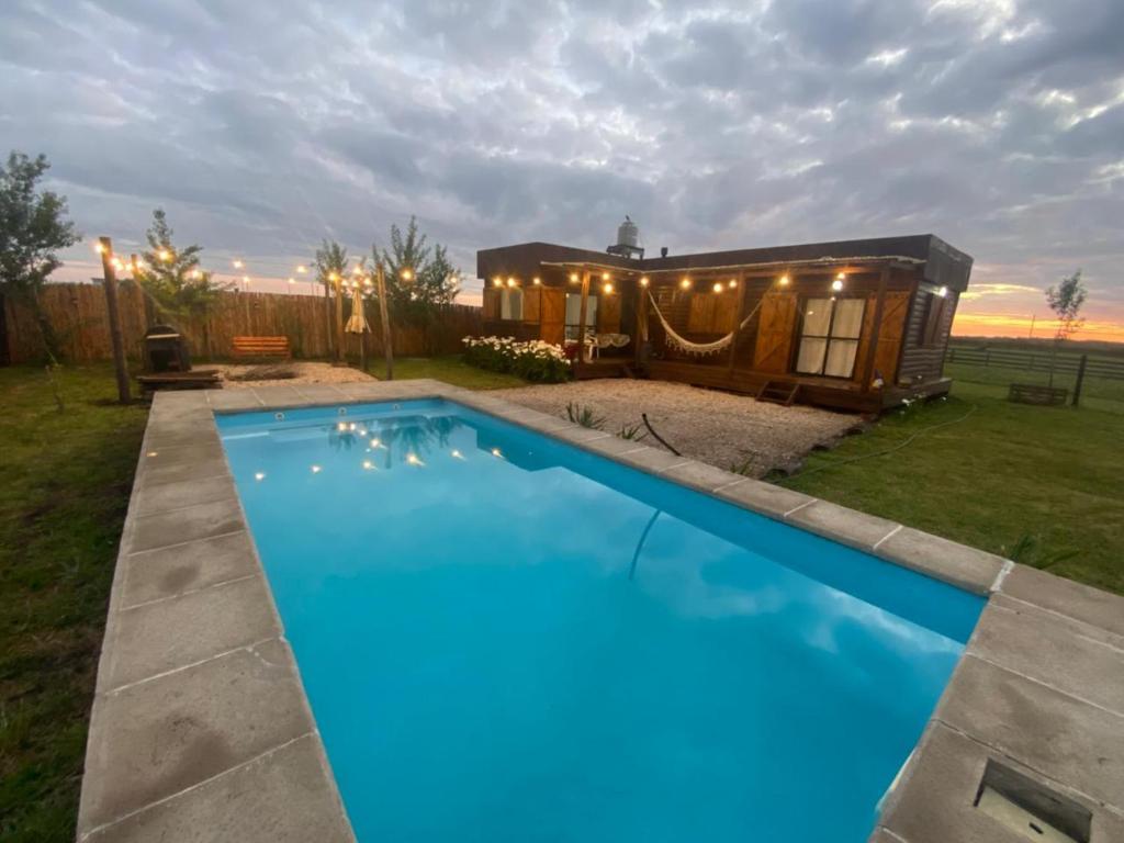 巴沙马拉尔Cabaña chapadmalal Nuestro rancho的一个小房子前面有一个大游泳池