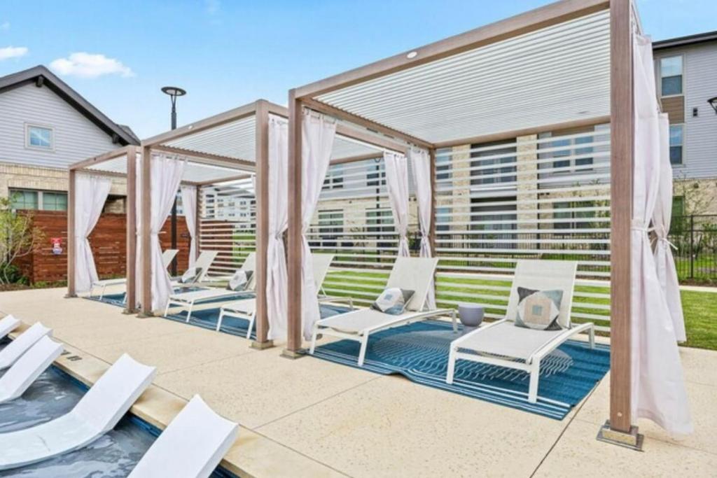 Un patio con sillas blancas y un cenador. en A plus Location WorkerFriendly KINGbed Pool Gym Modern, en Sherman