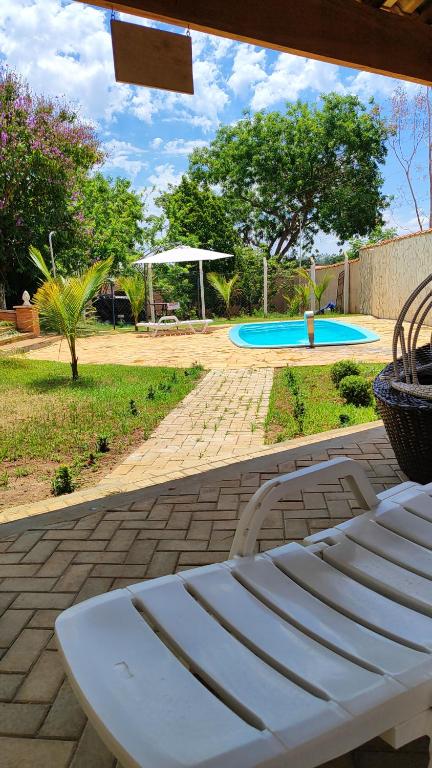 a white bench sitting on a patio next to a pool at Chalés Chácara Santa Felicidade 4 in Olímpia