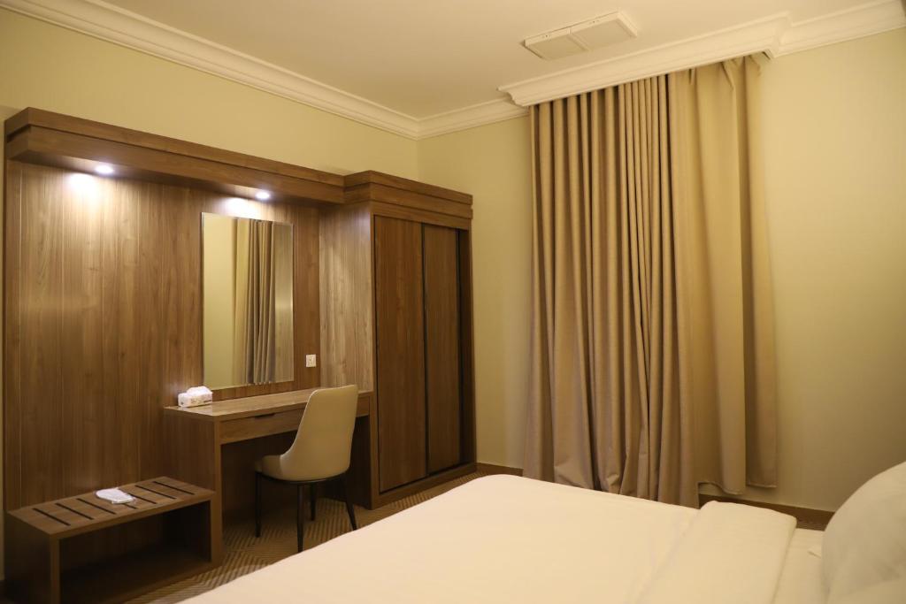 une chambre d'hôtel avec un lit, un bureau et un miroir dans l'établissement Taraf Yanbu 2, à Yanbu
