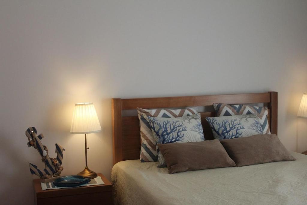 a bedroom with a bed with a lamp and pillows at Quiaios Beach House in Quiaios