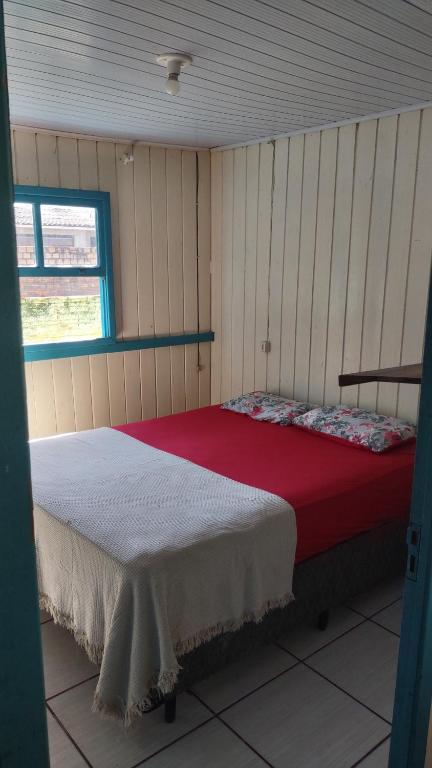 a bedroom with a bed with a red and white blanket at Casa de Boneca perto da praia in Imbituba