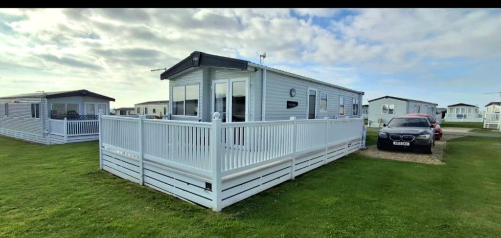 a white house with a car parked in a yard at Blue Lagoon Holiday ,Bude 79 in Cubert