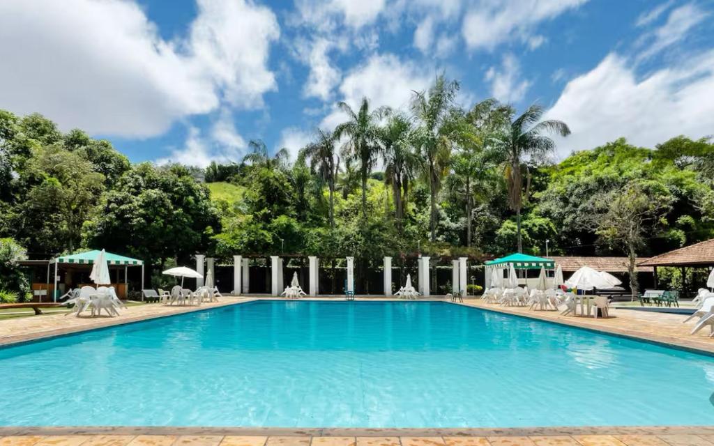 basen w ośrodku wypoczynkowym z krzesłami i parasolami w obiekcie Apartamento 122 no Condomínio Quisisana w mieście Poços de Caldas