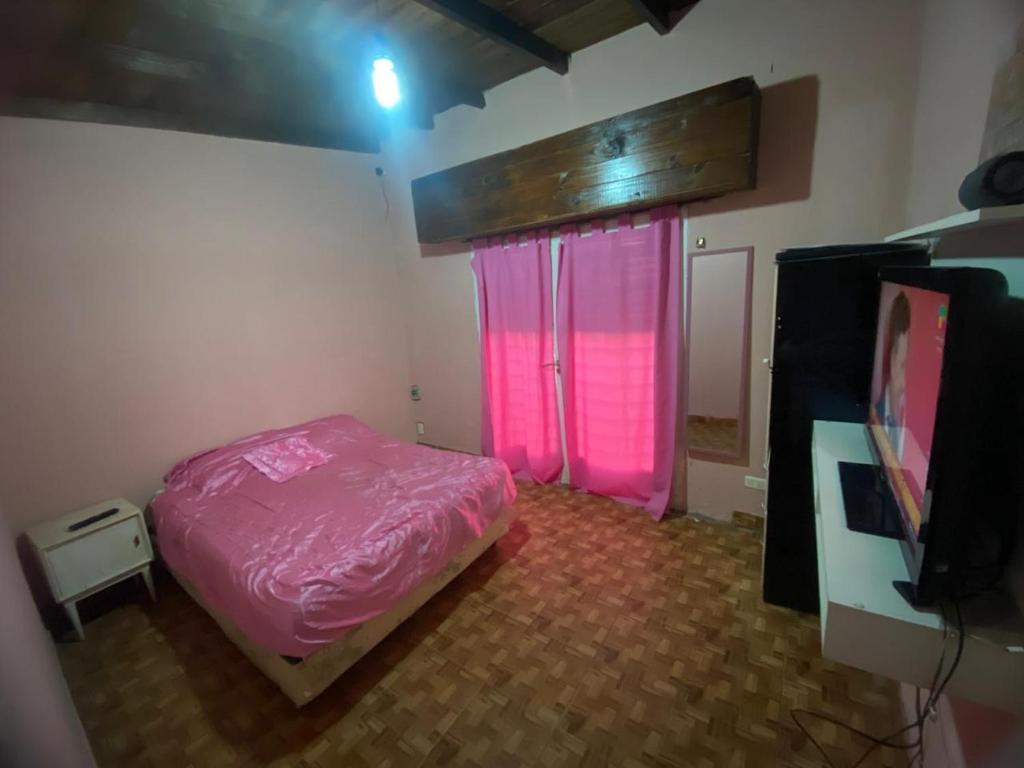 ein Schlafzimmer mit einem rosa Bett und einem TV in der Unterkunft Florencia in Miramar