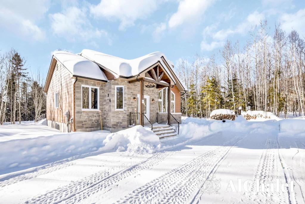 una casa de madera en la nieve con nieve en Natur Rustik - En pleine nature avec Spa, en Petite-Rivière-Saint-François