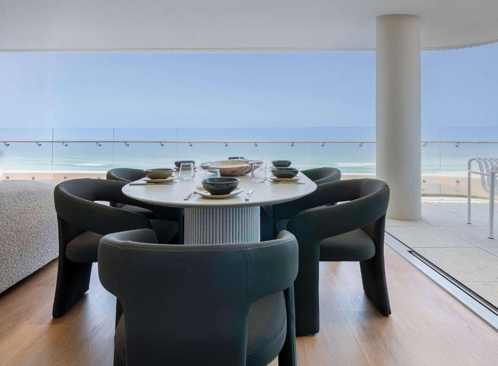 a dining room with a table and chairs and the beach at Monet by Khove - Kirra Beach in Gold Coast