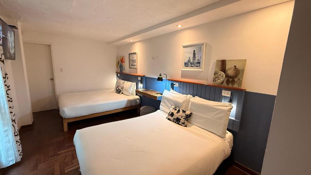 a hotel room with two beds and a desk at La Casa del Viajero in Lima