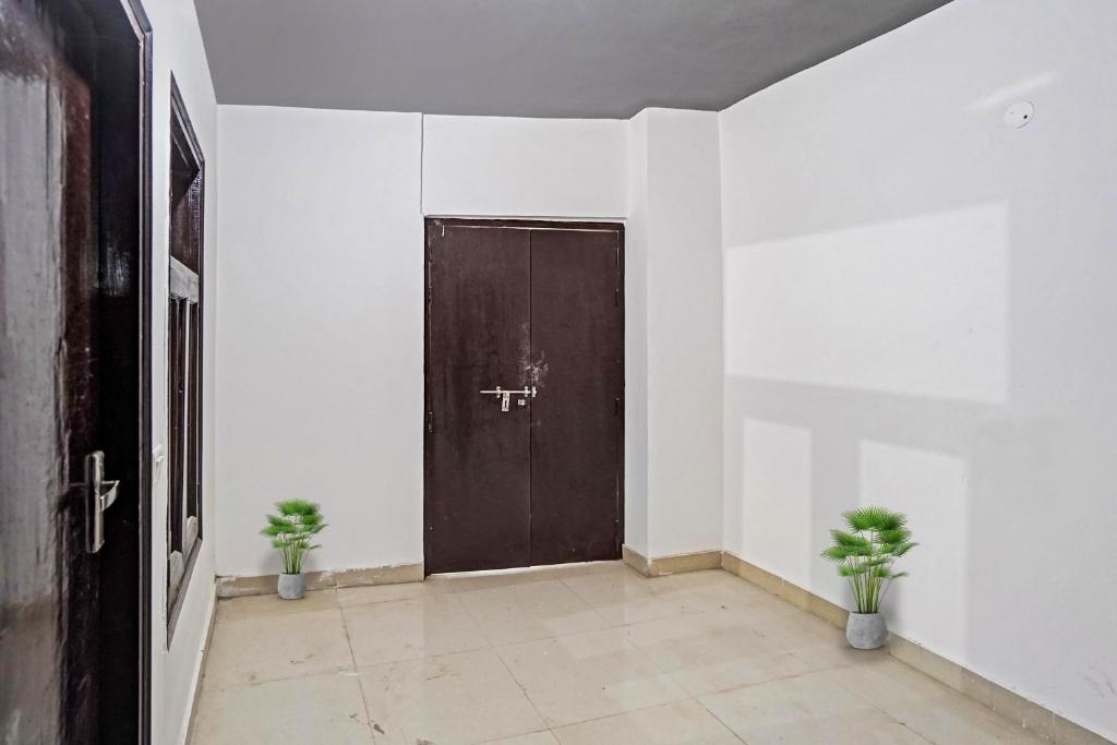 a door in a room with two potted plants at Hotel O Sunrise Villa in New Delhi